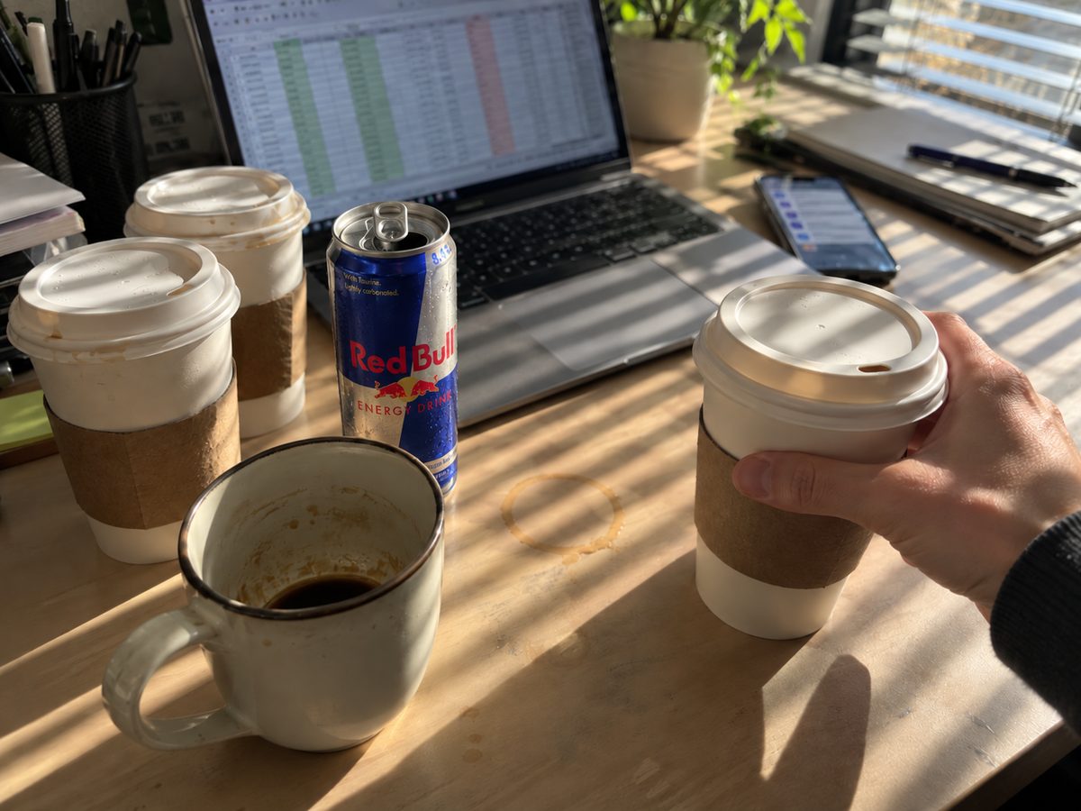 Coffee cups and an energy drink next to a spreadsheet