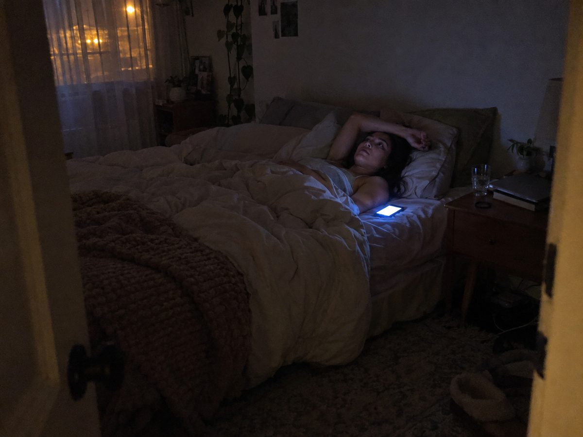 Awake in bed late at night, phone lit up